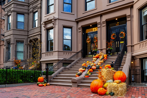 Boston, Massachusetts, USA - October 12, 2023: The steps of a two Back Bay brownstone  buildings lined with pumpkins and gourds, and wreaths on front doors, celebrating the Autumn season.