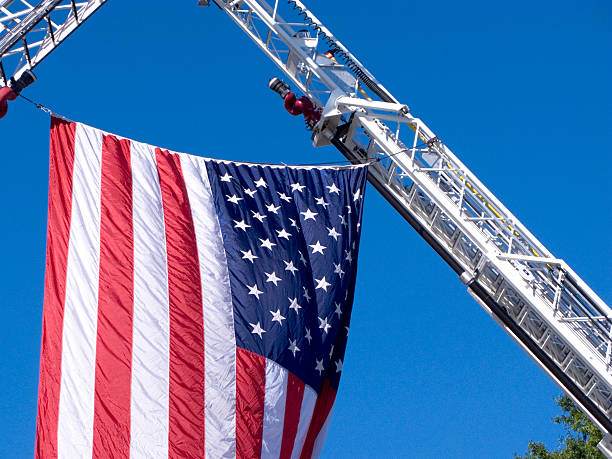 Hugh American Flag suspended from two fire engines ladder trucks.