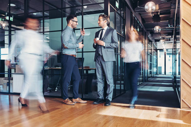 istock Two businessmen having a conversation while people are walking in the office 1739274128