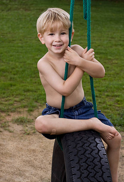 Little boy on tire swing smiling looking at camera stock photo
