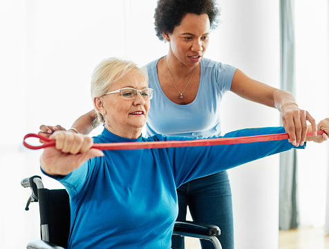 Doctor or nurse or physiotherapist caregiver exercise with senior woman at clinic or nursing home