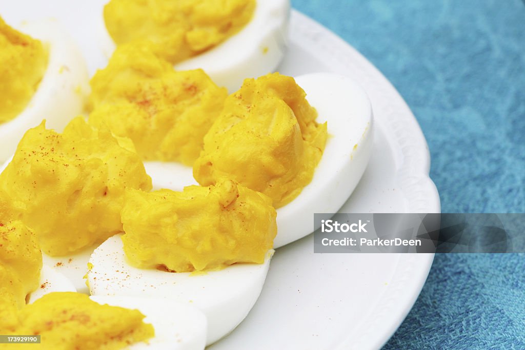 Deviled Eggs "Beautiful bright yellow deviled eggs on white plate on a bright aqua blue tablecloth.  Spring has arrived!Shot with Canon 30D, copy space available" Appetizer Stock Photo