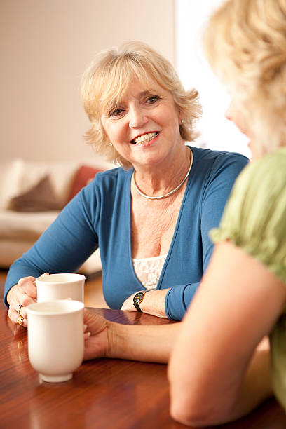 istock Two senior women seated, talking, with coffee cups 173929458