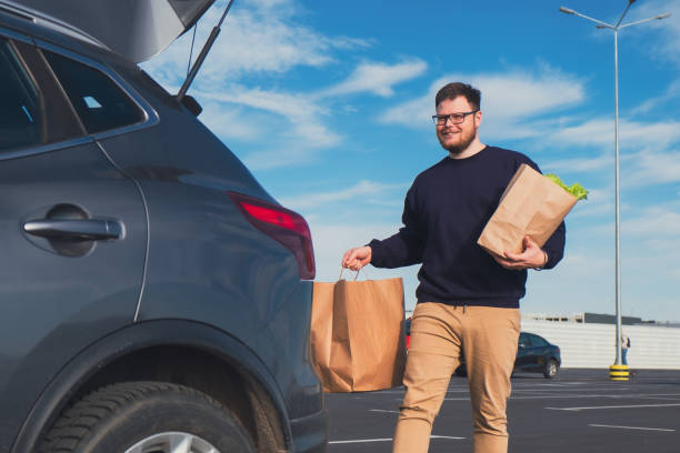 istock happy man put groceries bag in car trunk 1739302244