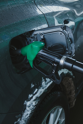 gas pump nozzle in car's fuel tank.