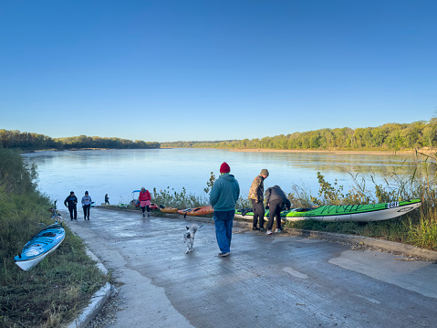 Hartsburg, MO, USA - October 7, 2023: Paddlers are preparing kayaks on a  boat ramp at sunrise to launch for a trip or race on the Missouri River.