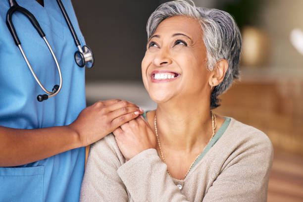 Nurse, senior woman and smile with comfort, holding hands or support in nursing home for retirement. Doctor, medic or caregiver with kindness, empathy or gratitude for help, trust or service in house stock photo