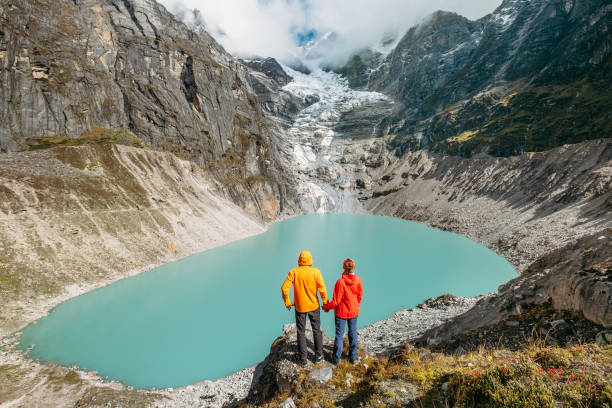 istock Trekkers couple dressed bright jwaterproof ackets stan on rock enjoying glacier falling in high altitude Sabai Tso glacial lake cca 4350m. Makalu Barun National Park, Mera peak climbing route, Nepal. 1739334900