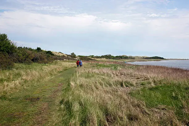 People walking in the nature reserve area on the Dutch isle of Ameland at the shore of the Wadden Sea.Photo taken in april 2009.
