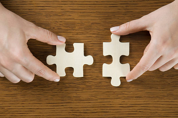 istock Two puzzle pieces about to fit together on a wooden surface 173933582
