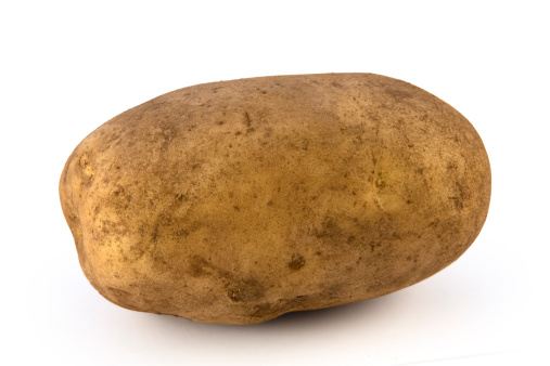 four boiled potatoes in their skins on a white background