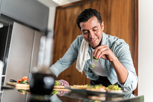 Mid adult man preparing toasted bread with guacamole at home