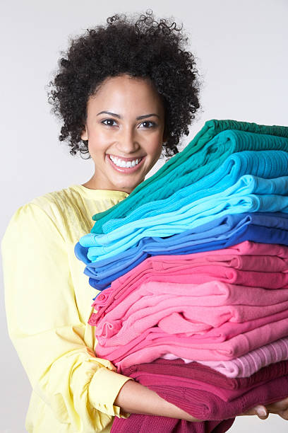 istock Smiling young woman holding stack of colorful clothes 173934328