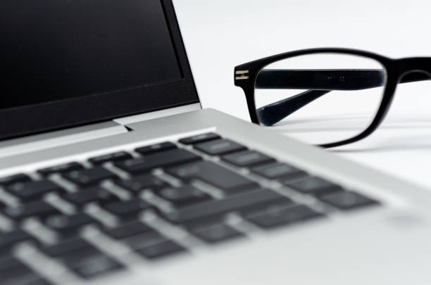 A laptop keyboard and glasses at work in an office