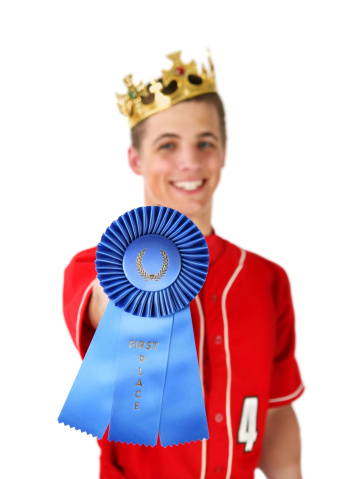Happy Teenage athlete with 1st Place award and crown. Shallow DOF with focus on rosette.