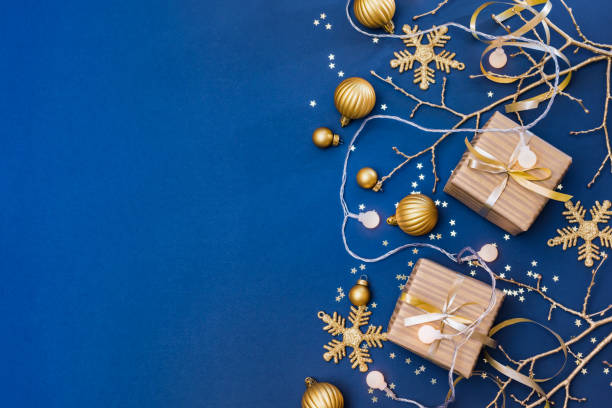 istock Flat lay christmas composition with golden gift box and christmas decorations, garland on a blue background. Winter holiday background with copy space 1739357446