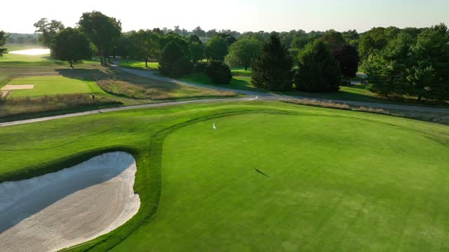 Golf course at sunset. Aerial shot of bunker and green of American country club.