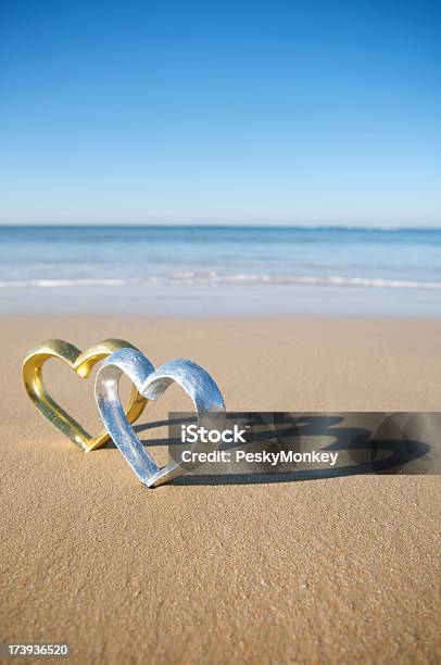Foto de Gold E Silver Corações Em Pé Juntos Na Praia e mais fotos de stock de Amor - Amor, Areia, Comemoração - Evento