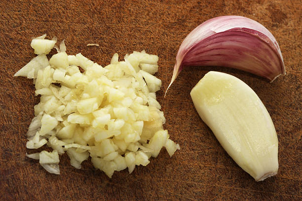 Finely chopped garlic on a wooden cutting board Chopped garlic on a chopping board  garlic stock pictures, royalty-free photos & images