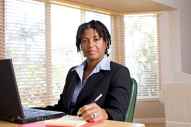 Smiling businesswoman with pen and laptop stock photo
