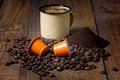 Mug of coffee with coffee beans, pods and ground coffee