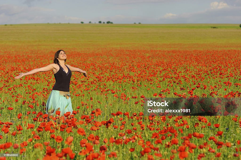 Mujer joven en un campo de amapolas - Foto de stock de 20 a 29 años libre de derechos