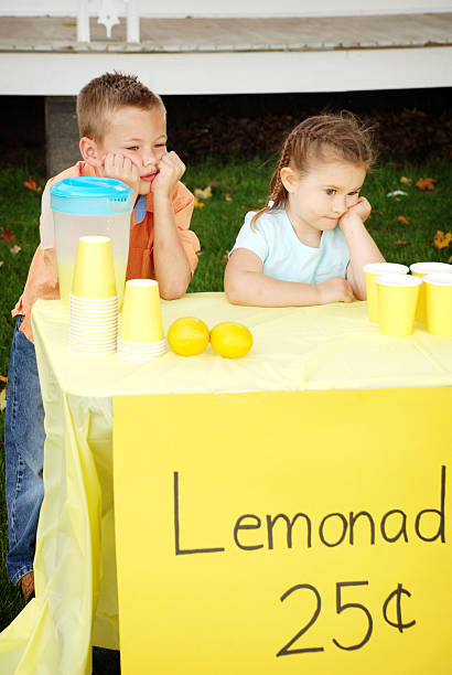 aborrecido rapaz e rapariga pé atrás da barraca de venda de limonada - lemonade stand lemonade child failure imagens e fotografias de stock