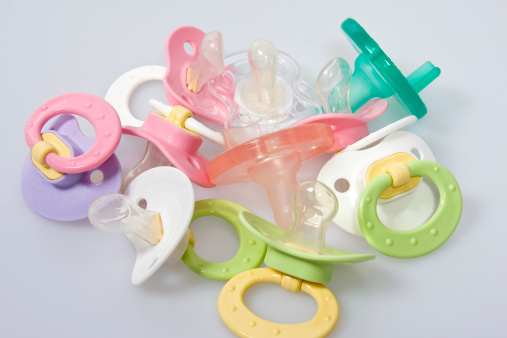 Various baby pacifiers and binkies (binky) displayed in a pile.