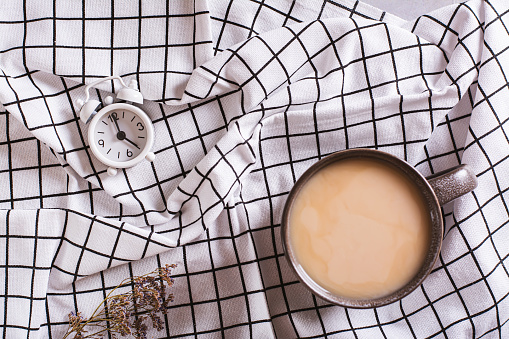 istock Change to winter time. Cup of coffee and alarm clock on checkered crumpled fabric top view 1739413719