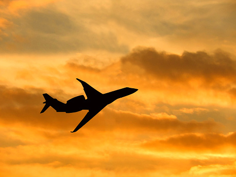 Silhouette of a private executive jet taking off against a winter sky at sunset. No people. Copy space. Travel concept.