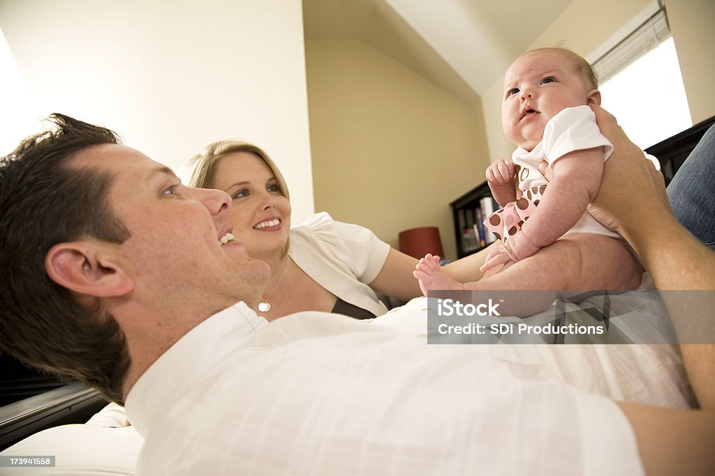 Happy Father And Mother Playing With Their Baby Girl Happy Young Father And Mother Laying Down Playing With Their Baby Girl.See more from this series: Adult Stock Photo