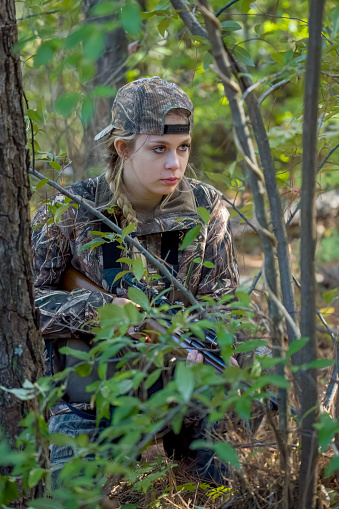 Beautiful young hunter girl with rifle in the woods