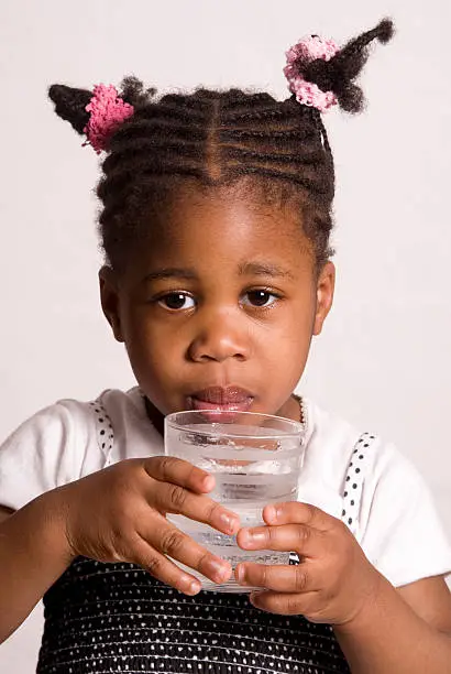 Little black girl drinks from a glass of water