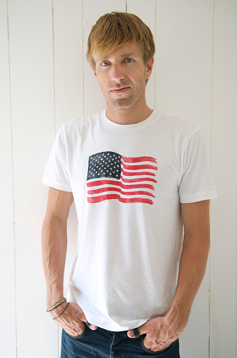 Guy in American flag T-shirt stands looking at the camera. 