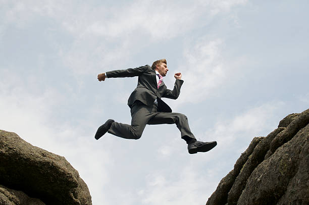 istock Courageous Businessman Leaping between Rocks 173943667