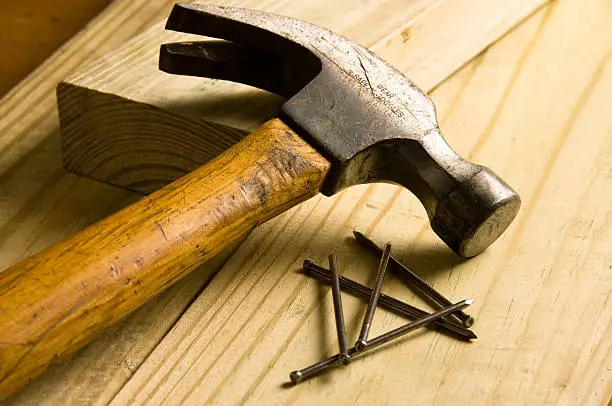 Photo of A hammer and nails on a wooden surface