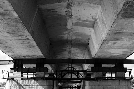 Concrete and steel details of a bridge span, perspective view. Abstract industrial architecture background. Black and white photo
