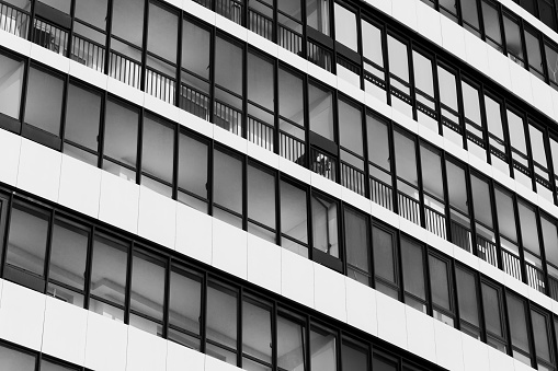 Abstract modern architecture background, white house wall with windows in rows. Black and white photo