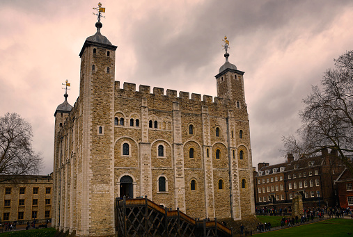 London, United Kingdom - April, 6 2023: View of the facade of the White Tower, inside the Tower of London against a cloudy sky at dusk.