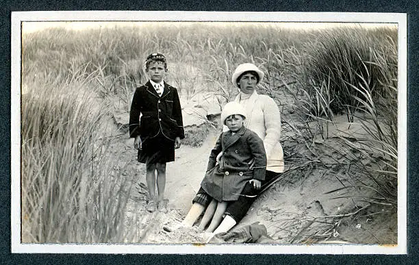"Vintage photograph of an Edwardian family on a day out at the seaside sitting in the sand dunes. Knokke, Belgium."