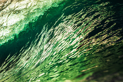 Close up detail of emerald green wave breaking in the ocean with warm morning light. Shot on the east coast of Australia.