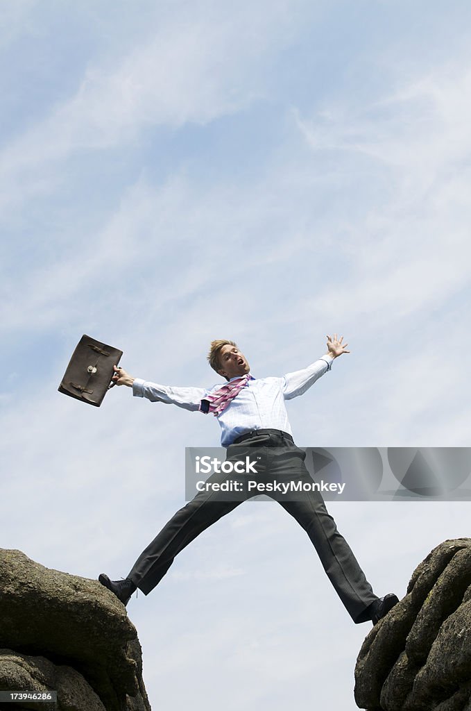 Geschäftsmann erstreckt sich über das Tal zwischen zwei Rocks - Lizenzfrei Aktentasche Stock-Foto