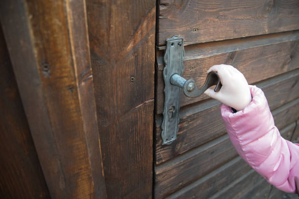 Woman using a house key on the front door. Close up of he womanâs hand. She is turning the key in the lock. There is a hallway in the  background. The key ring has a house icon on it.