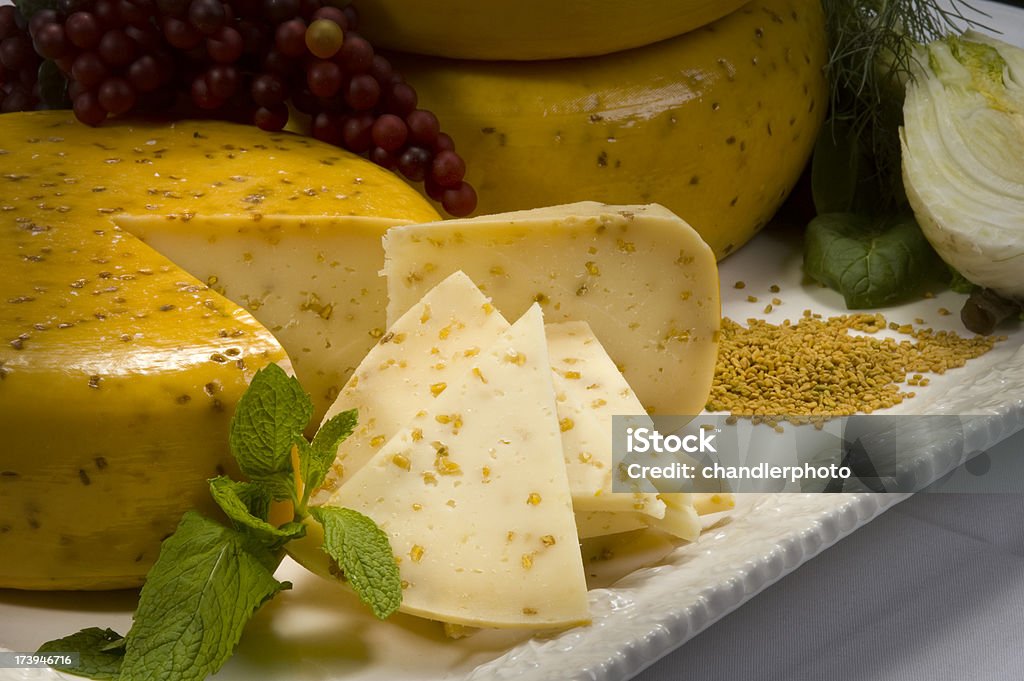 Sliced Cheese Wheel "Gouda cheese with cumin or mustard seeds, served on a tray for a party." Gouda Cheese Stock Photo