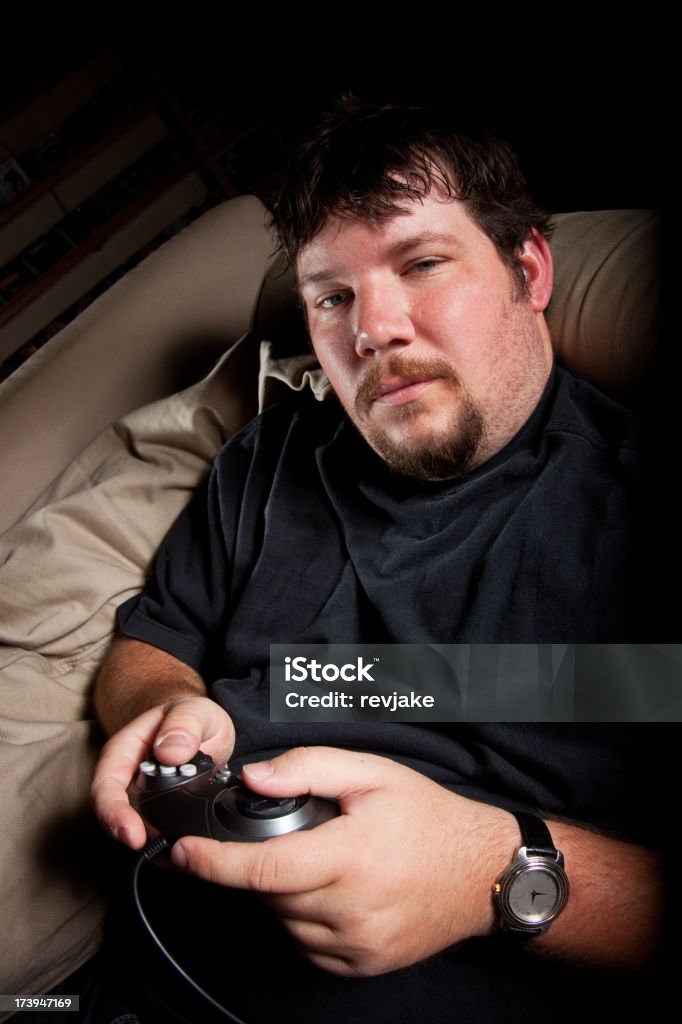 Hombre en SOFÁ jugando un videojuego - Foto de stock de 20-24 años libre de derechos