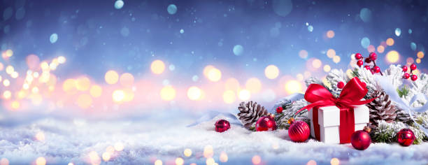 Gift Box On Snow With Bokeh Lights And Ornament In Fir Branch - Merry Christmas stock photo