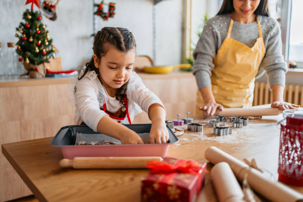 istock Little Girl Making Christmas Cookies Using Cookie Cutter With Her Mother 1739483776
