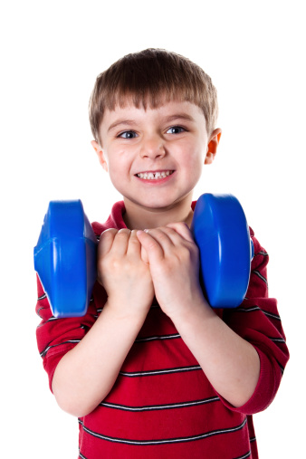 A young boy shows his strength by lifting a dumbell over his head. XXXL Image size.