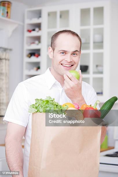 Groceries And Man In Kitchen Eating Apple Stock Photo - Download Image Now - Adult, Adults Only, Apple - Fruit