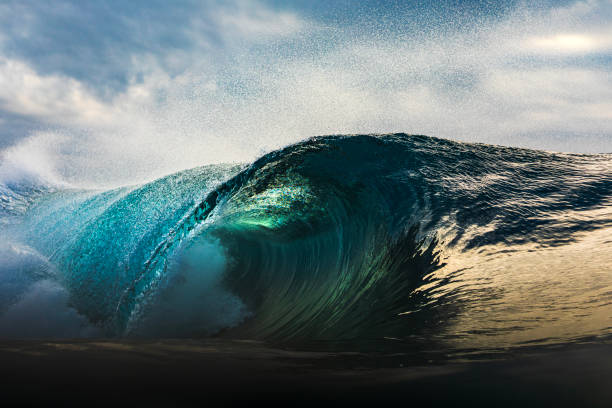 istock Powerful blue wave breaking in the ocean with a dark cloudy, sky 1739490412